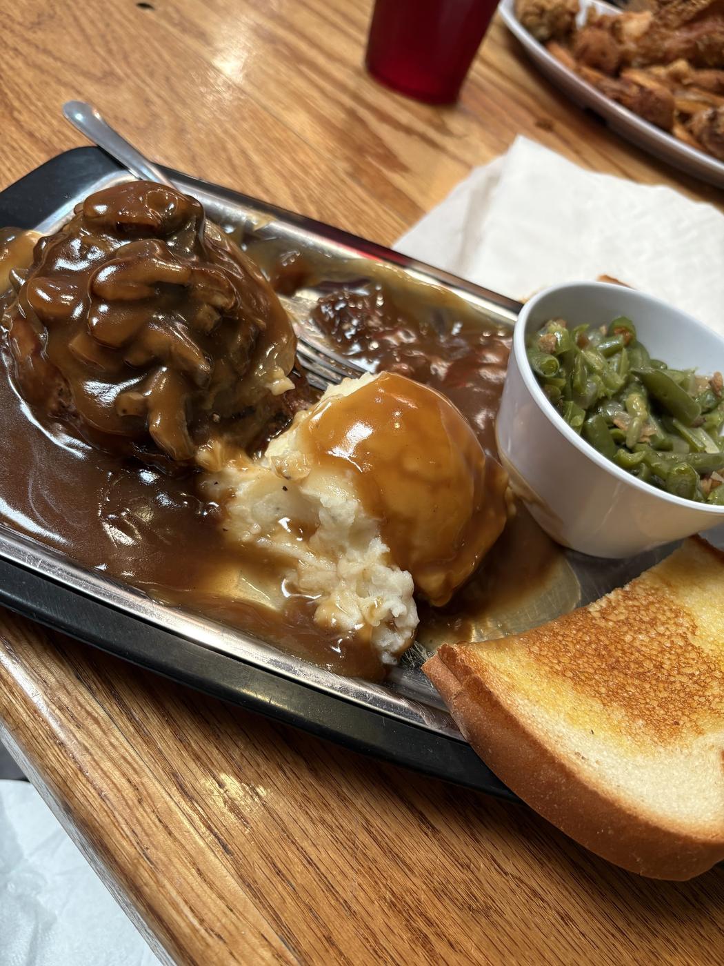 Hamburger steak under mushroom gravy with mashed potatoes, green beans and Texas toast